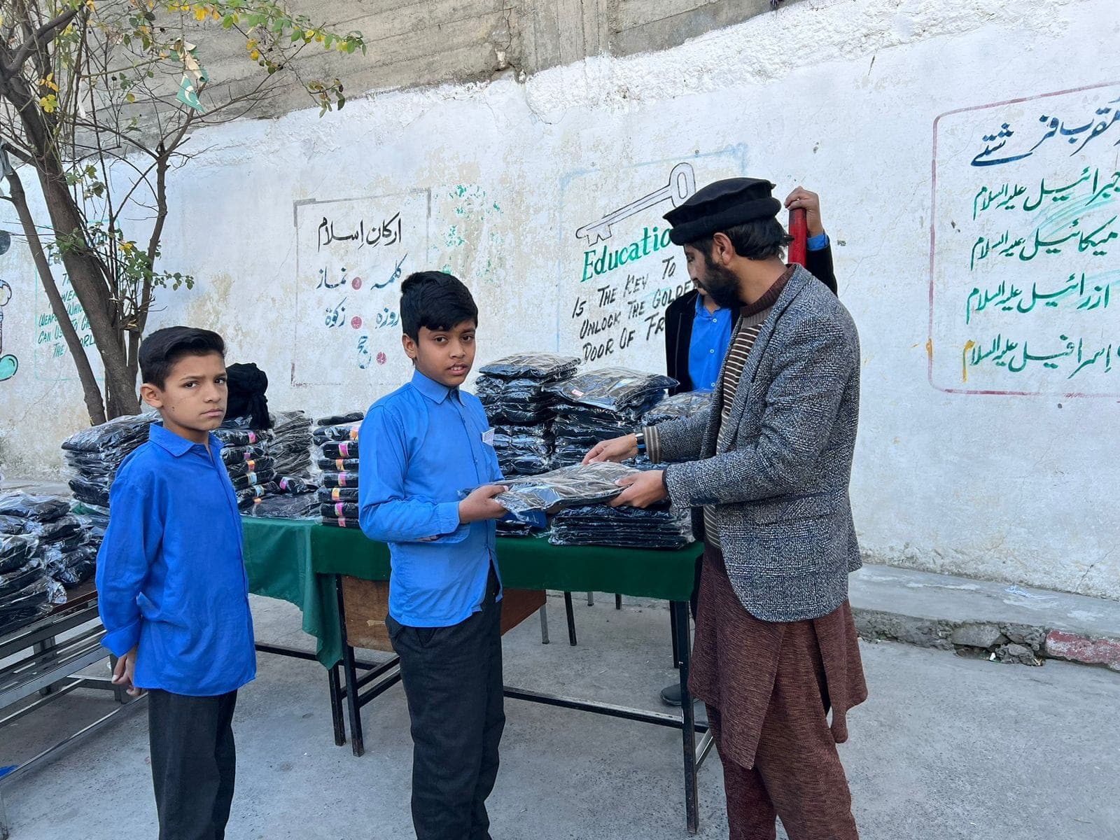 A volunteer handing a new sweater to a schoolboy at our December 2023 uniform drive