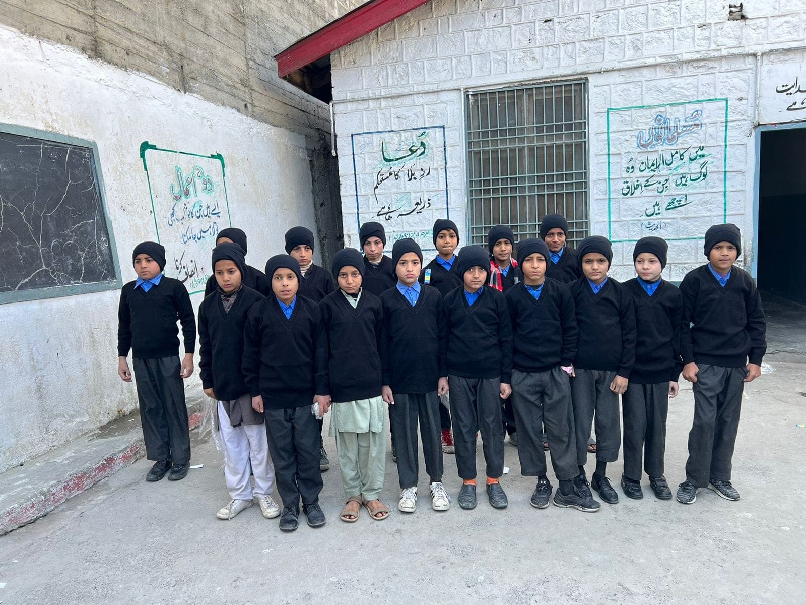 Schoolboys lined up in the new sweaters and caps from our December 2023 uniform drive
