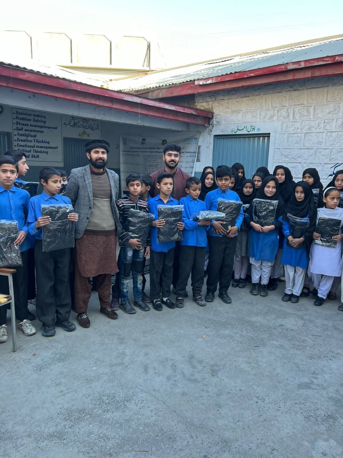 Schoolchildren holding the warm sweaters we handed out in December 2023